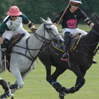 Two men riding horses and playing polo