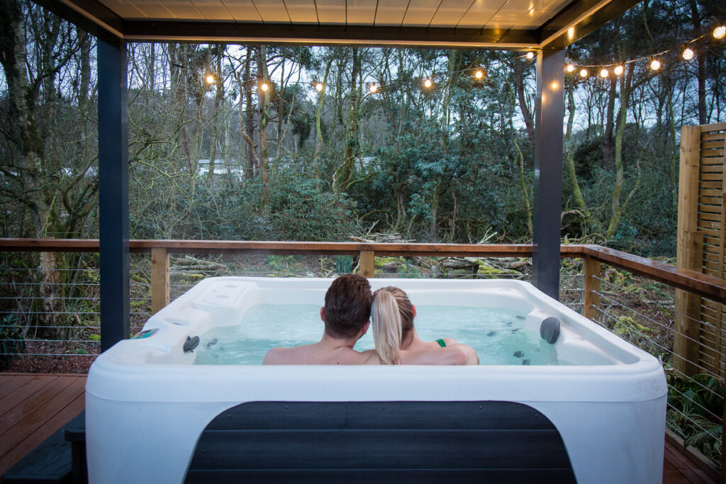 A couple relaxes in a hot tub at one of our Blakemere Hideaways